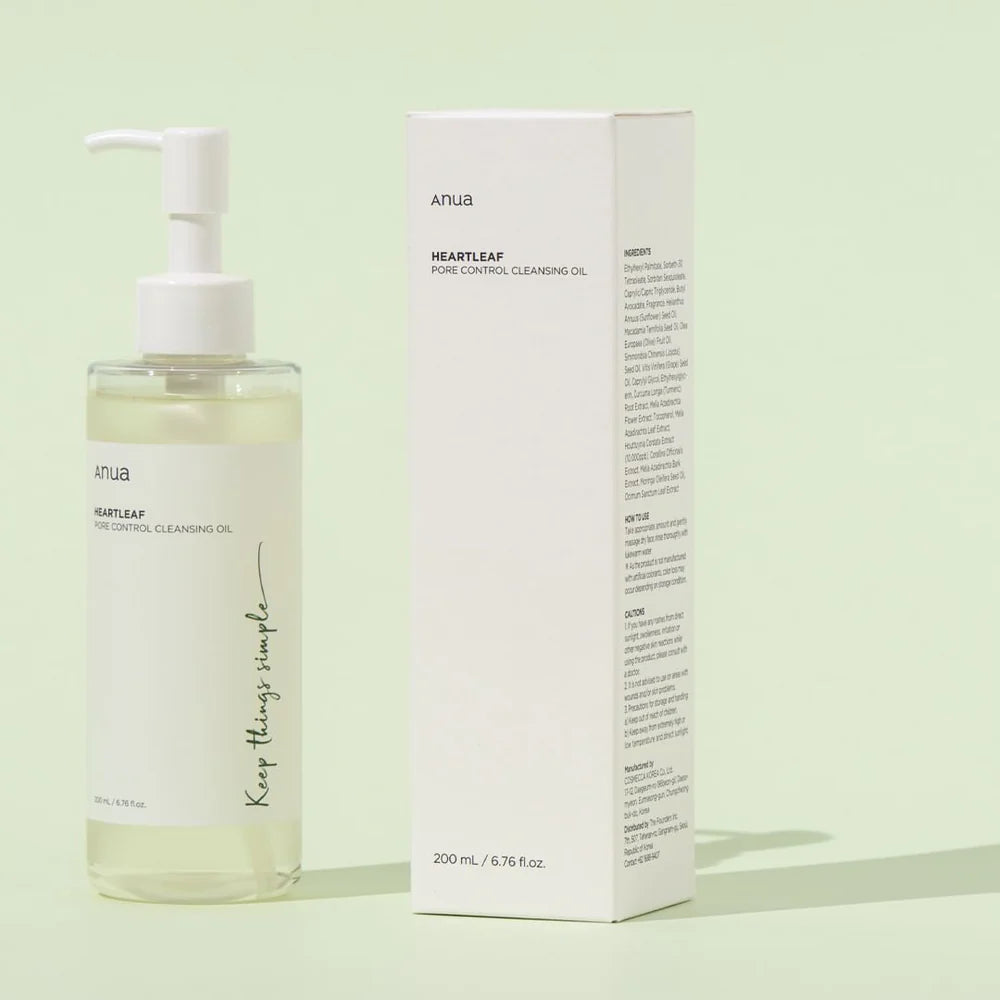 Anua Heartleaf Pore Control Cleansing Oil – ansigtsrens - gennemsigtig plastflaske med hvid pumpe og hvid etiket står oprejst på en lys baggrund. Ved siden af flasken står produktets papkasse, som er hvid med grønne og sorte detaljer.