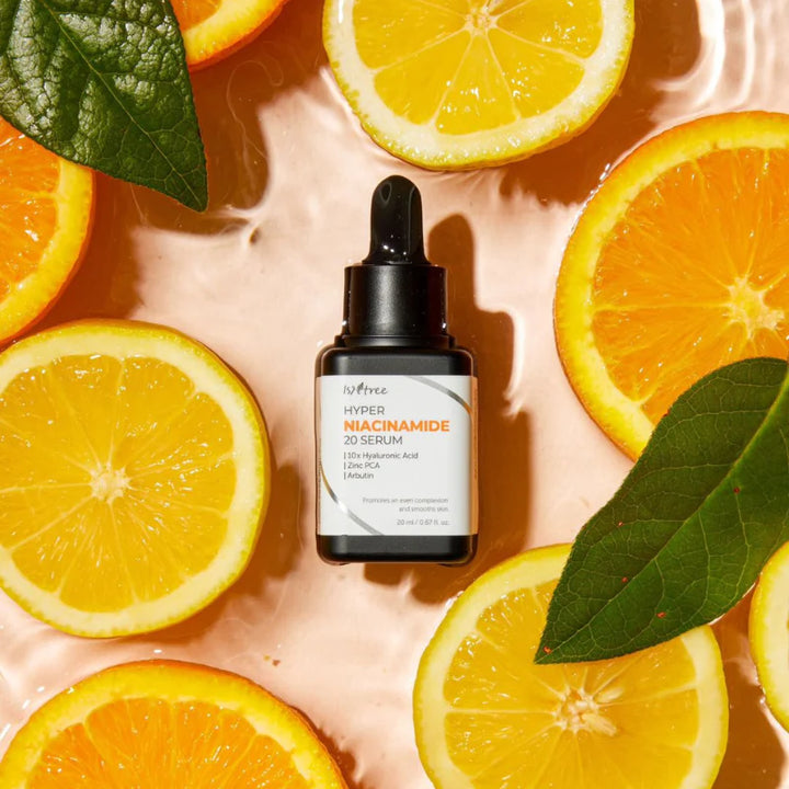 Isntree - 
Hyper Niacinamide 20 Serum - stærkt hudplejeprodukt ligger på en baggrund med halve appelsiner. pipette flasken er sort og ediketten er hvid med sort og orange skrift