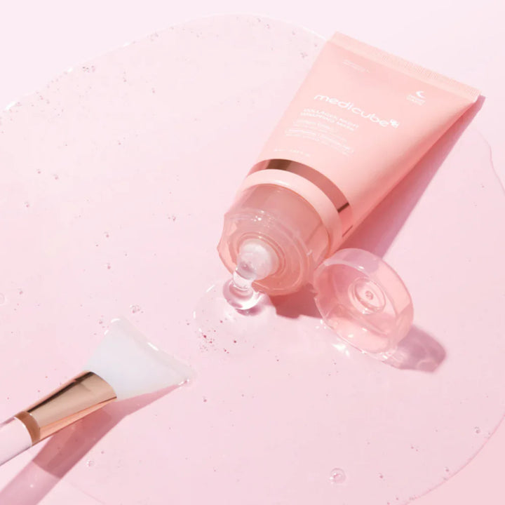 Medicube - 
Collagen Night Wrapping Mask - hudpleje sovemaske ligger på et bord og er åben. der kommer noget ansigts maske ud på bordet